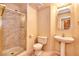 Cozy bathroom with glass door shower, marble wall tiles, a pedestal sink, and toilet at 9413 Cedar Heights Ave, Las Vegas, NV 89134