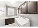 Well-equipped laundry room with built-in cabinets, sink, and a front-load washer and dryer at 1129 Via Della Curia, Henderson, NV 89011