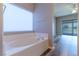 Bathroom featuring a tiled soaking tub with a large window and access to the main bedroom at 1195 Golf Club Dr, Laughlin, NV 89029