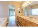 Bathroom featuring double sinks, a soaking tub, and wood-finish cabinetry with a view of the bedroom at 1195 Golf Club Dr, Laughlin, NV 89029