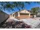 A single-story home with a one-car garage, neutral trim, and desert landscaping, shaded by a mature tree with a long driveway at 1905 Eskam St, Las Vegas, NV 89156