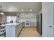 Modern kitchen boasts sleek white cabinets, quartz countertops, stainless steel appliances, and wood-look flooring with bar seating at 1905 Eskam St, Las Vegas, NV 89156