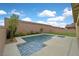 A backyard pool with concrete surround, small yard, and block wall under a blue sky at 404 Lost Horizon Ave, Henderson, NV 89002