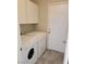 This laundry room has a washer, a dryer, tile flooring and white cabinets at 4718 Victoria Garden Ave, North Las Vegas, NV 89031
