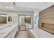 Bright bathroom featuring walk in shower, bathtub, and dual sinks with wood accent wall at 5008 Shoal Creek Cir, Las Vegas, NV 89113