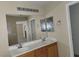 Bathroom featuring double sinks with white countertops and wood cabinets, illuminated by modern vanity lighting at 5052 Whistling Acres Ave, Las Vegas, NV 89131