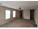 Neutral-toned living room with carpeted floors and ceiling fan, stairs visible in background at 5052 Whistling Acres Ave, Las Vegas, NV 89131