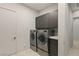 Well-equipped laundry room featuring gray cabinetry, modern washer and dryer units and a white door at 515 Serenity Point Dr, Henderson, NV 89012