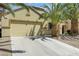 Inviting single-story home with a two-car garage, complemented by palm trees and desert landscaping at 520 Blackbird Knoll Ct, North Las Vegas, NV 89084