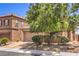 Two-story home with two-car garage, desert landscaping, and a mature shade tree in the front yard at 5528 Stone Lagoon St, North Las Vegas, NV 89031