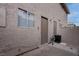 Small backyard with tan stucco exterior and utility access door with a black trash receptacle at 573 Sellers Pl, Henderson, NV 89011