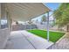 A covered back patio offering a cozy outdoor living space with green turf and privacy wall at 5834 Autumn Harvest Ave, Las Vegas, NV 89142