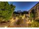 Cozy backyard illuminated at night, featuring lush landscaping, flagstone path, and a charming bench at 6140 Galileo Dr, Las Vegas, NV 89149