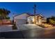Attractive home with stone accents, a three-car garage, and manicured front yard with illuminated steps to front door at 6140 Galileo Dr, Las Vegas, NV 89149