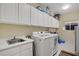 Bright laundry room with sink, modern washer and dryer units, and ample cabinet space at 6140 Galileo Dr, Las Vegas, NV 89149