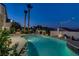 Stunning backyard pool illuminated at twilight, featuring lush landscaping and mature palm trees at 6140 Galileo Dr, Las Vegas, NV 89149