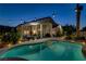 Backyard pool at dusk with lush landscaping, mature palm trees, and cozy outdoor lighting at 6140 Galileo Dr, Las Vegas, NV 89149