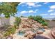 Beautiful rock waterfall feature leading to a pool and surrounded by desert landscaping in backyard at 6140 Galileo Dr, Las Vegas, NV 89149