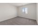 A simple bedroom with a neutral carpet, and a window that looks out into the neighborhood at 6197 Blood Lily Ave, Las Vegas, NV 89122