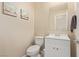 Clean and simple half bathroom with a white vanity, toilet, and decorative artwork at 6788 Sharks Bay Ct, Las Vegas, NV 89149