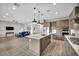 Bright open kitchen features stainless appliances, large island with marble counters, and stylish pendant lighting at 6865 Steel Mist St, Las Vegas, NV 89148