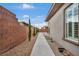 Spacious side yard with concrete walkway, landscaped gravel area, and brick privacy wall at 6865 Steel Mist St, Las Vegas, NV 89148