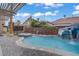 A backyard pool with a slide and waterfall feature and a lounge area under a pergola at 7621 Hackensack Ct, Las Vegas, NV 89128