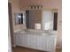 Bathroom vanity featuring double sinks, white cabinets, tile flooring and large mirror at 9709 Port Orange Ln, Las Vegas, NV 89134