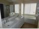 Bathroom vanity featuring double sinks, white cabinets, tile flooring and soaking tub at 9709 Port Orange Ln, Las Vegas, NV 89134