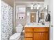 Well-lit bathroom featuring white tile flooring, floral shower curtain, and wooden vanity with modern fixtures at 10508 Snyder Ave, Las Vegas, NV 89134