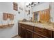 Bathroom featuring wood vanity with granite countertop, decorative towels, and mirrors at 10674 Chillingham Dr, Las Vegas, NV 89183