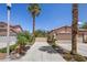 Inviting desert home with a long driveway, a two-car garage, and lush tropical landscaping at 10674 Chillingham Dr, Las Vegas, NV 89183