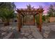 Wooden pergola with a swing, set in a serene backyard garden with stone pathways at 10674 Chillingham Dr, Las Vegas, NV 89183