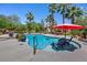 Backyard pool area with seating, landscaped plants, and mature palm trees at 10674 Chillingham Dr, Las Vegas, NV 89183
