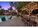 Outdoor kitchen and bar overlooking a refreshing swimming pool and lush landscaping at 10674 Chillingham Dr, Las Vegas, NV 89183