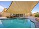 Sparkling pool with a shade sail, surrounded by a patio area and lush landscaping at 155 Fallon Dr, Henderson, NV 89074
