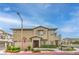 Exterior view of tan two-story townhouse with brick accents, attractive landscaping, and a red tile roof at 173 Petaluma Valley Dr, Las Vegas, NV 89138