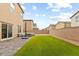 Spacious backyard with artificial grass, a stone patio, lounge seating and a brick perimeter wall at 4039 Beech Fern Ave, North Las Vegas, NV 89084