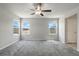 A bright bedroom with plush carpeting, large windows, and a ceiling fan, adjacent to an ensuite bathroom at 4039 Beech Fern Ave, North Las Vegas, NV 89084
