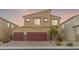A two-story home with a neutral color scheme, a three car garage, desert landscaping and a brick driveway at 4039 Beech Fern Ave, North Las Vegas, NV 89084