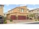Two-story home with a tan exterior, three car garage, desert landscaping and brick driveway at 4039 Beech Fern Ave, North Las Vegas, NV 89084