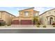 Tan two-story home with a three car garage, desert landscaping, and brick driveway at 4039 Beech Fern Ave, North Las Vegas, NV 89084