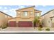 Two-story home with a neutral color scheme, three car garage, desert landscaping, and a brick driveway at 4039 Beech Fern Ave, North Las Vegas, NV 89084