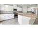 Bright kitchen featuring stainless steel appliances, a kitchen island with granite countertop and ample white cabinetry at 4039 Beech Fern Ave, North Las Vegas, NV 89084