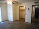 Bedroom with damage to walls, ceiling fan, sliding glass door, carpet flooring, closet, and entry into another room at 5006 Schumann Dr, Las Vegas, NV 89146