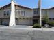 Multi-story stucco townhome featuring a terracotta roof, arched windows, attached garages, and groomed landscaping at 5006 Schumann Dr, Las Vegas, NV 89146
