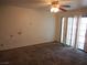 Living room with damaged walls, ceiling fan, sliding glass doors for natural light, and carpet floors at 5006 Schumann Dr, Las Vegas, NV 89146