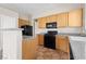 Functional kitchen with wood cabinets, granite counters, black appliances, and ample counter space at 5307 Wild Orchid St, North Las Vegas, NV 89031