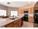 This well-lit kitchen features an island with a double sink and sleek black appliances at 5835 Running Horse Dr, North Las Vegas, NV 89081