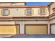 View of the garages with tan doors, red trim, and yellow shuttered windows at 5950 Barbosa Dr # 8, North Las Vegas, NV 89031